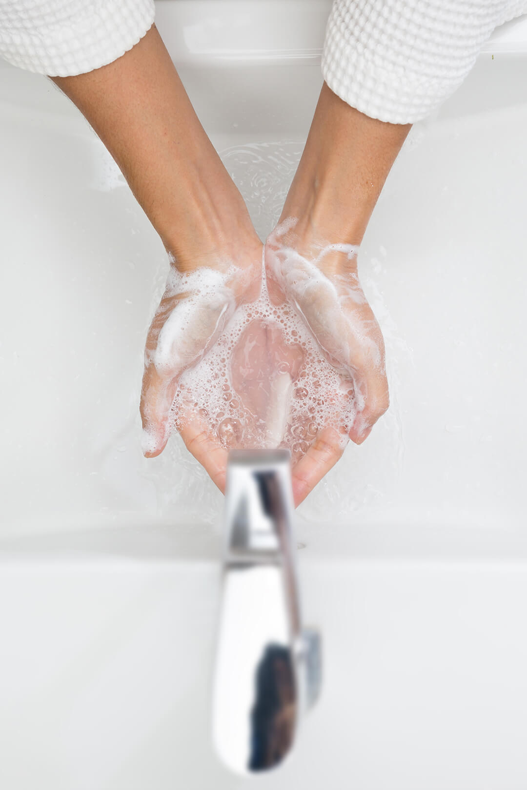 Soapy hands under tap