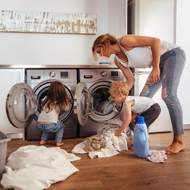 Woman loading washing machine with her two children