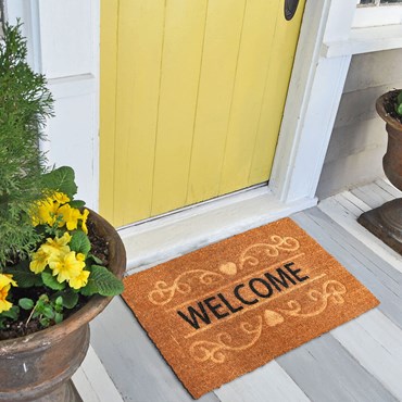 Brown welcome mat in front of yellow door