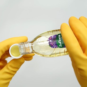 Zoflora being poured into cap held by yellow rubber gloves