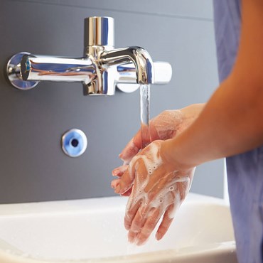 Hands washed under tap with soap