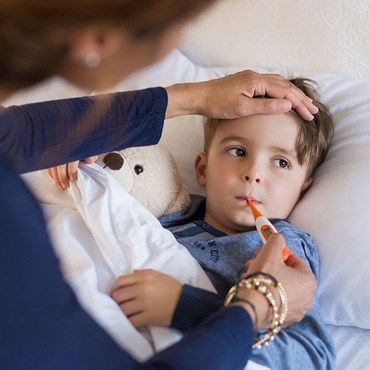 Mum putting thermometer in child's mouth