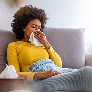 Woman under blanket with tissues