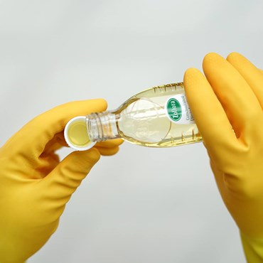 Zoflora bottle poured into cap held by yellow rubber gloves